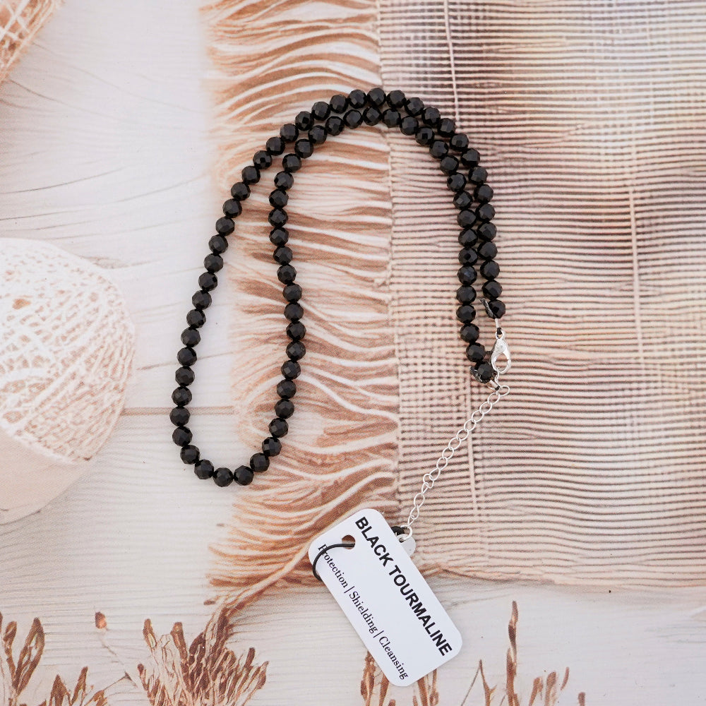 Black beaded necklace with a tag on a textured surface