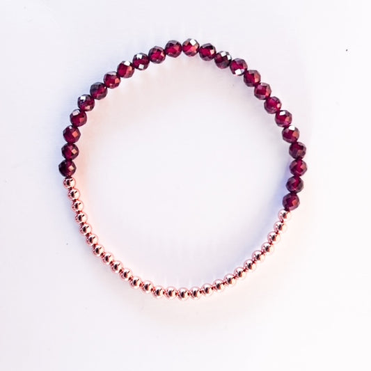 Stretch bracelet with garnet beads, 3mm copper beads and elastic wire on a white background