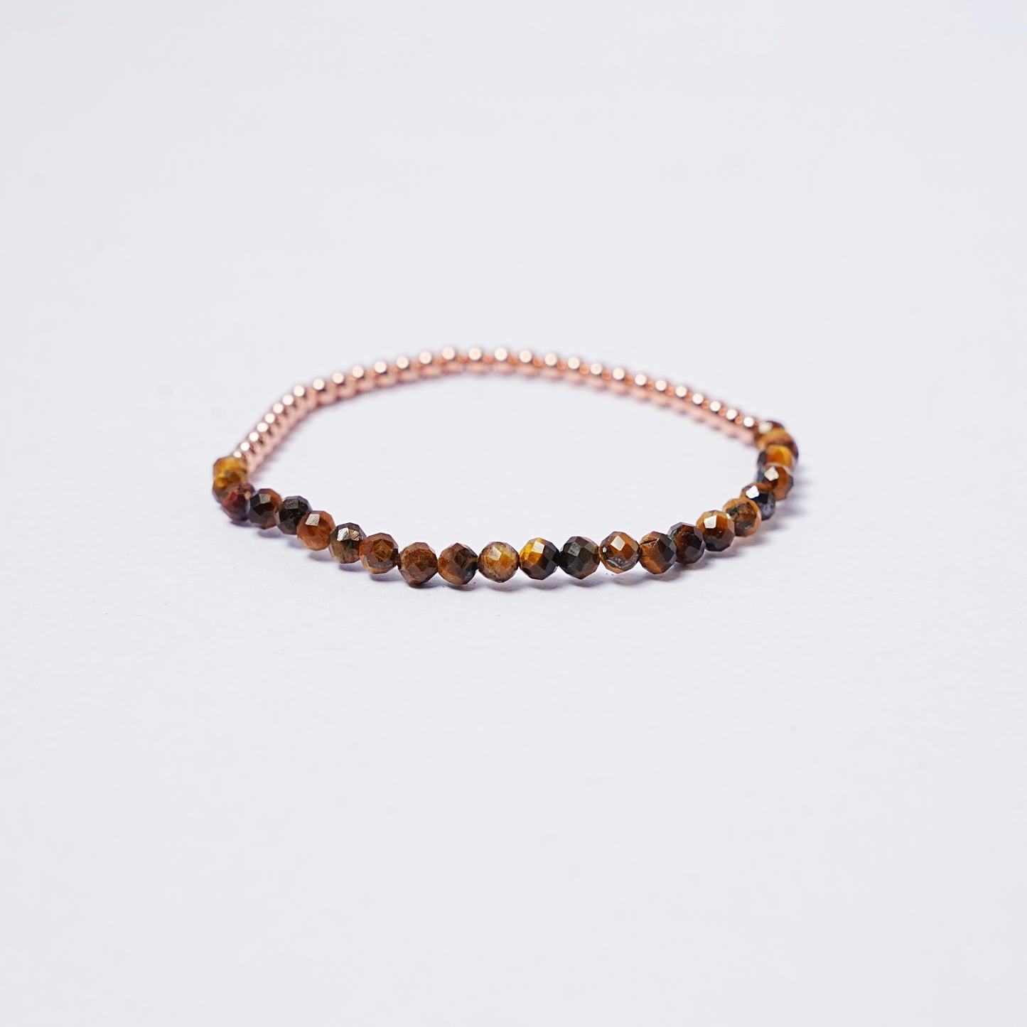 Stretch bracelet with tiger's eye beads, 3mm copper beads and elastic wire on a white background