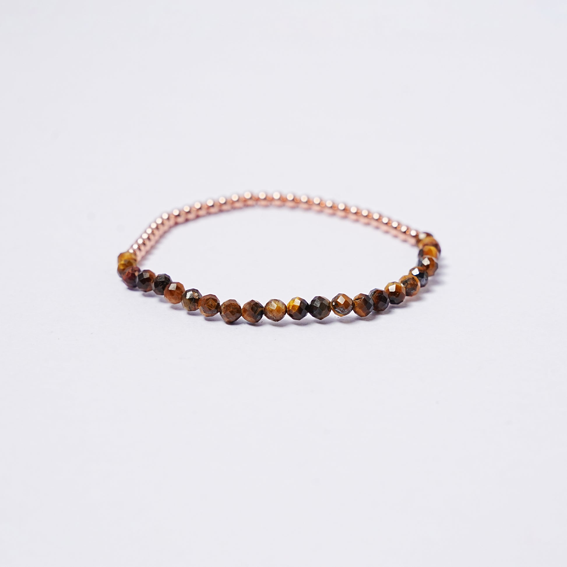 Stretch bracelet with tiger's eye beads, 3mm copper beads and elastic wire on a white background