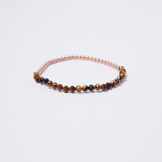 Stretch bracelet with tiger's eye beads, 3mm copper beads and elastic wire on a white background