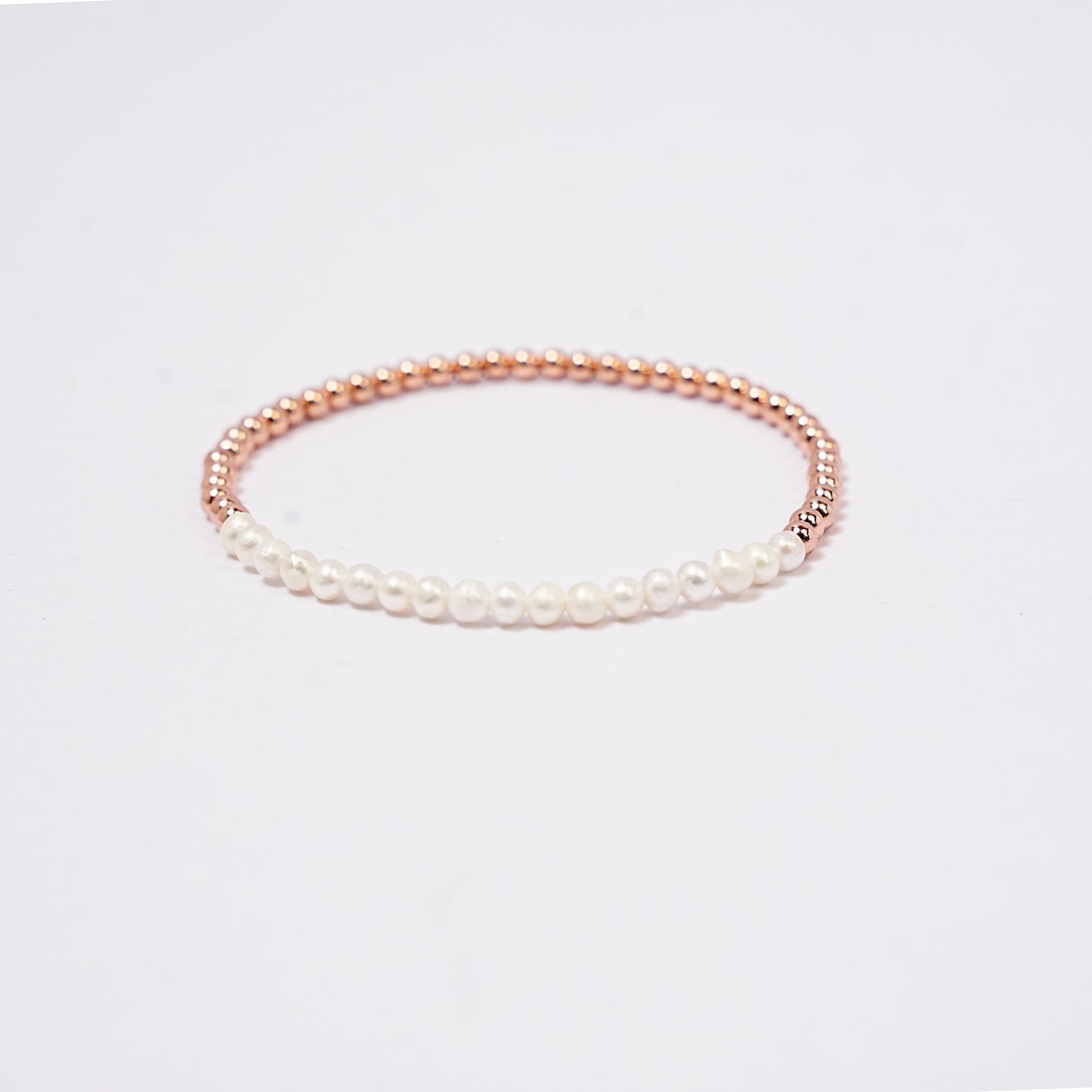 Stretch bracelet with pearl beads, 3mm copper beads copper beads and elastic wire on a white background     
