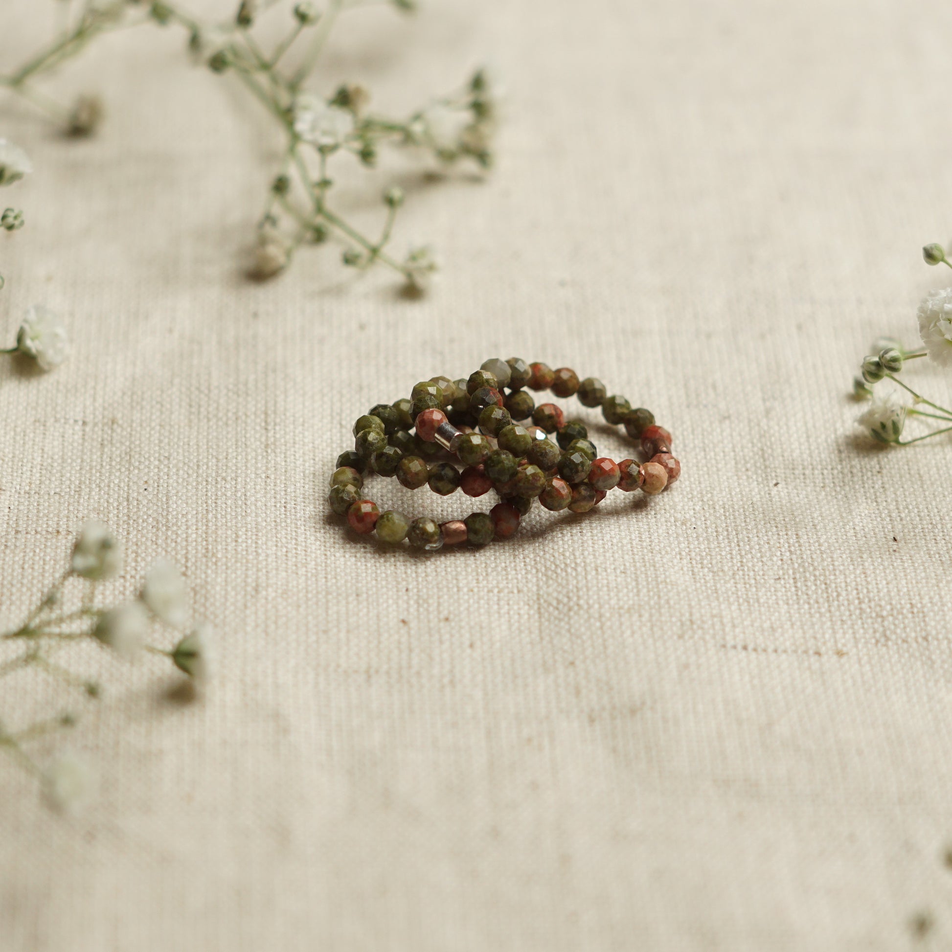 light green beaded with 'The Blue Yogi'  unakite rings on a natural background