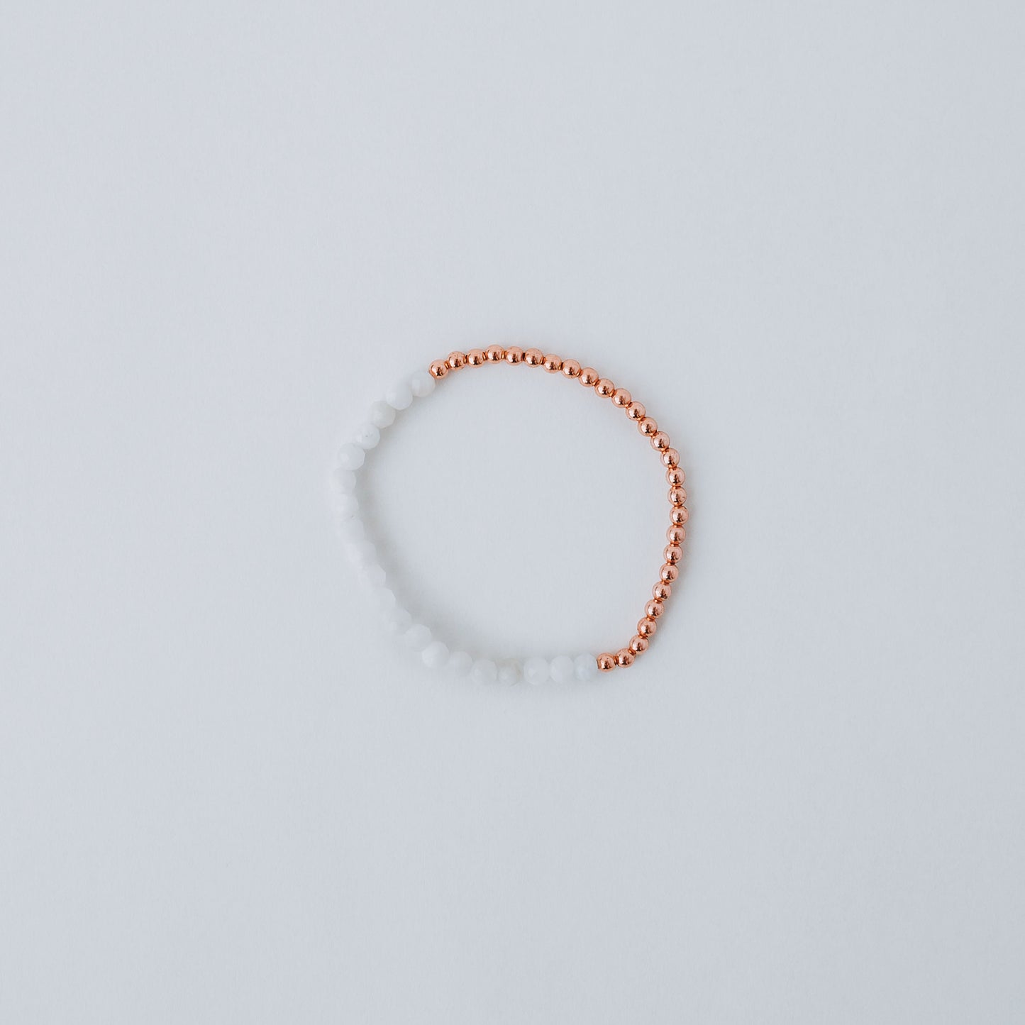 Stretchy bracelet with moonstone beads, 3mm copper beads and elastic wire on a white background