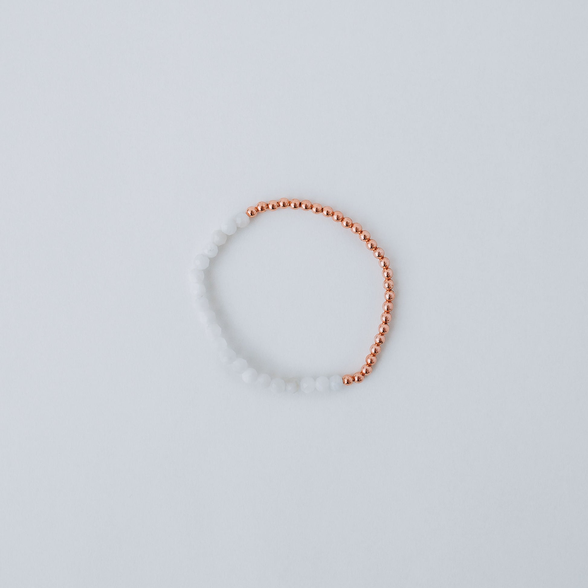 Stretchy bracelet with moonstone beads, 3mm copper beads and elastic wire on a white background